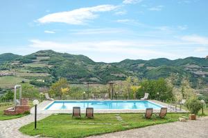 a swimming pool with chairs and mountains in the background at Agriturismo - Tenuta MonteOliveto - Cottage Romantic in Vesime