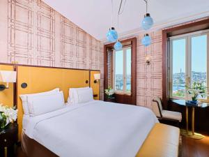 een slaapkamer met een groot wit bed en ramen bij The Galata Istanbul Hotel MGallery in Istanbul