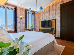 a bedroom with a large bed and a flat screen tv at The Galata Istanbul Hotel MGallery in Istanbul