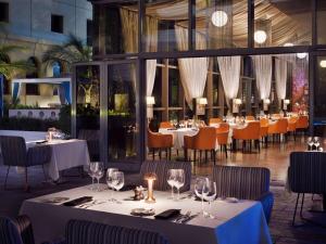 un restaurante con mesas y sillas blancas y ventanas en Mövenpick Hotel Jumeirah Beach, en Dubái
