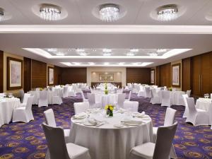 un salón de banquetes con mesas blancas y sillas blancas en Mövenpick Hotel Jumeirah Beach en Dubái