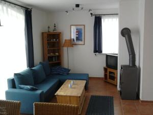 uma sala de estar com um sofá azul e uma televisão em Ferienhaus Seepferdchen Neßmersiel em Neßmersiel