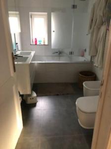 a bathroom with a tub and a toilet and a sink at Stay in maison de metre in Etterbeek in Brussels