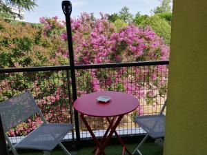 einen Tisch und Stühle auf einem Balkon mit rosa Blumen in der Unterkunft Appartdom in Angoulême
