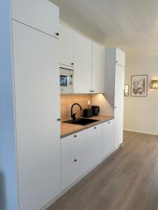 una cocina con armarios blancos y fregadero en Brand New! Villa Moon en Rovaniemi