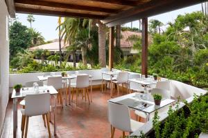 un restaurante con mesas blancas y sillas en un patio en Parque San Antonio, en Puerto de la Cruz