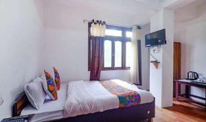 a bedroom with a bed with a window and a television at FabExpress Laxmi Niwas in Gangtok