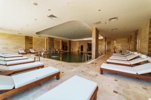 a room with a pool and a bunch of chairs at Anadolu Hotels Esenboga Thermal in Esenboga