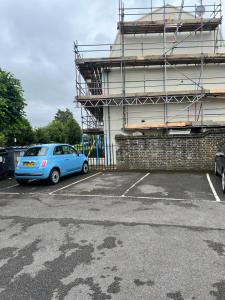a blue car parked in a parking lot next to a building at Central Canterbury Apartment with Parking in Kent