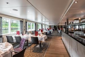 ein Restaurant mit weißen Tischen, Stühlen und Fenstern in der Unterkunft KD Hotelschiff Messe und Stadion in Düsseldorf