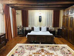 a bedroom with a bed with white sheets and a rug at Pensiunea Rozalia in Criţ