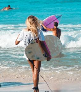 Eine Frau, die mit einem Surfbrett am Strand spazieren geht. in der Unterkunft Bamboo Surf Beach in San Isidro