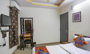 een slaapkamer met een bed en een bureau met een stoel bij THE EDEN HOTEL Near Okhla in New Delhi