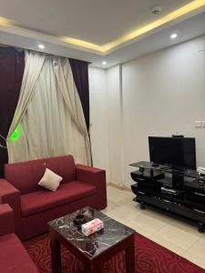 - un salon avec un canapé rouge et une télévision dans l'établissement فندق أسس التاج, à Abou Arish