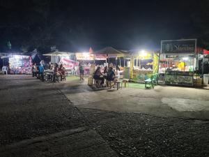 un grupo de personas sentadas en mesas en un mercado por la noche en Rotunda Inn home stay, en Pagadían​