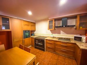 eine Küche mit Holzschränken, einem Tisch und einer Mikrowelle in der Unterkunft Casa de Ina in Outes