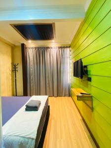 a bedroom with green walls and a bed and a tv at Suza Hostel in Tumpat