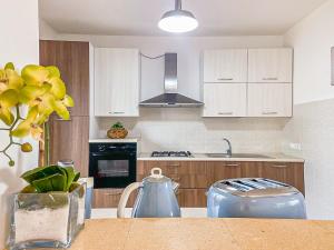 a kitchen with white cabinets and a vase with yellow flowers at * [Stalettì] *La casa sul mare* in Stalettì