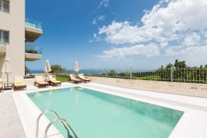 einen Pool mit Stühlen und ein Gebäude in der Unterkunft Vigla Suites in Rethymno