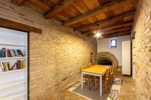 uma sala de jantar com uma mesa e uma parede de tijolos em Relais Castel d'Emilio - Casa VERDE em Cassero