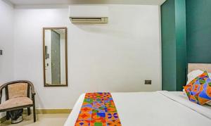 1 dormitorio con cama, espejo y silla en FabExpress Rama, en Nueva Delhi