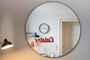 einen Spiegel in einem Zimmer mit einer Uhr an der Wand in der Unterkunft SCHWARZLINS LoftRaum - Stilvolles Apartment mit Smart TV, NETFLIX, Disney Plus, schnellem WLAN, Parken, Nespresso in Sankt Ingbert