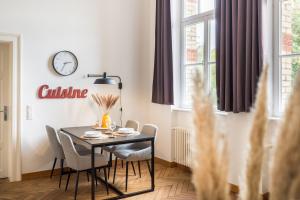 mesa de comedor con sillas y reloj en la pared en SCHWARZLINS LoftRaum - Stilvolles Apartment mit Smart TV, NETFLIX, Disney Plus, schnellem WLAN, Parken, Nespresso, en Sankt Ingbert