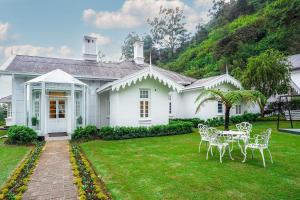 Casa blanca con mesa y sillas en el patio en The Clovelly Bungalow, en Nuwara Eliya