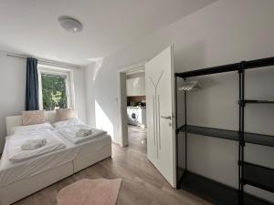a white bedroom with a bed and a window at FeelHome-GolfClub-Balkon-4 Gäste-WiFi-Smart TV in Ebreichsdorf