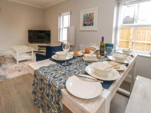 a dining room with a table with plates and wine glasses at 3 Compass Point in Weymouth