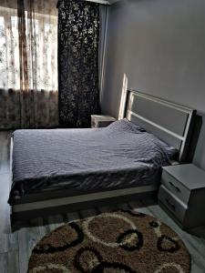 a bedroom with a bed with a rug and a window at Квартира в Алматы . 23 in Almaty
