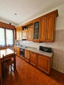 - une cuisine avec des placards en bois et une table dans l'établissement Appartamento Jever House, à Rigolato