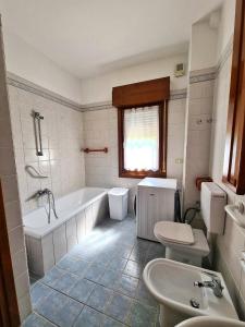 a bathroom with a tub and a toilet and a sink at Appartamento Jever House in Rigolato +4 photos