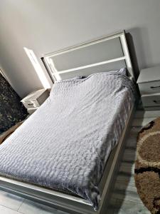- un lit dans une chambre avec une couette grise dans l'établissement Квартира в Алматы . 23, à Almaty