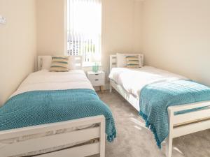 two beds in a white room with a window at 3 Compass Point in Weymouth