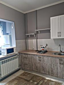 a kitchen with wooden cabinets and a sink and a microwave at Квартира в Алматы . 23 in Almaty