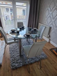 a dining room with a glass table and white chairs at Luxury on a Budget in Chelmsford