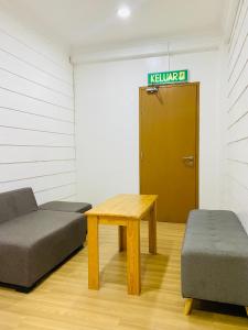 a room with a couch and a table and a door at Suza Hostel in Tumpat