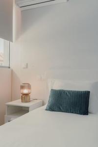 Cama blanca con almohada azul y lámpara en Lux in Porto en Oporto
