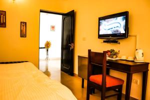 1 dormitorio con 1 cama y escritorio con TV en Van Durga Villas & Suites, en Padmi