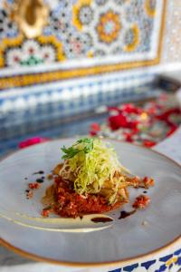 a white plate with a dish of food on a table at RIAD GOLD in Azrou