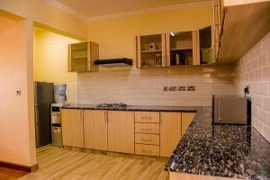 a kitchen with wooden cabinets and a black counter top at TJ's Boutique Hotel in Eldoret