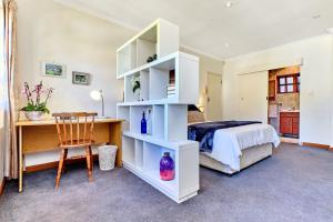 Lonehill - Deluxe Garden Cottage 2 في Sandton: غرفة نوم مع رف كتاب أبيض بجوار سرير