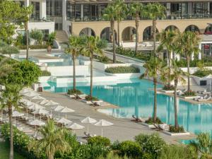 an overhead view of a resort pool with chairs and umbrellas at Grecotel Lux Me Dama Dama in Faliraki