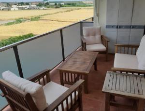 d'un balcon avec des chaises et des tables offrant une vue sur un champ. dans l'établissement APARTAMENTO EN ALESANCO-LARIOJA, à Alesanco