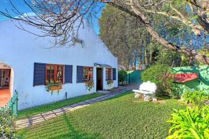 una casa bianca con una panchina in cortile di Lonehill - Deluxe Garden Cottage 2 a Sandton