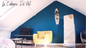 a room with a yellow chair and a surfboard on a blue wall at La Cabane De Pol in Dunkerque