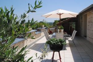 un patio con mesa, sombrilla y sillas en Gîte Matran, en Cauna