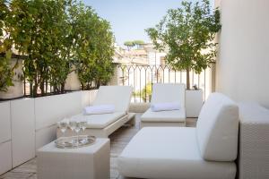 a patio with white chairs and tables on a balcony at Amazing 3 Levels Penthouse Piazza Venezia in Rome