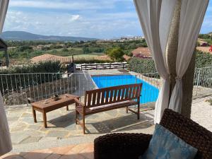 Villa Nanà في تانايونيلا: مقعد وطاولة على شرفة مع مسبح